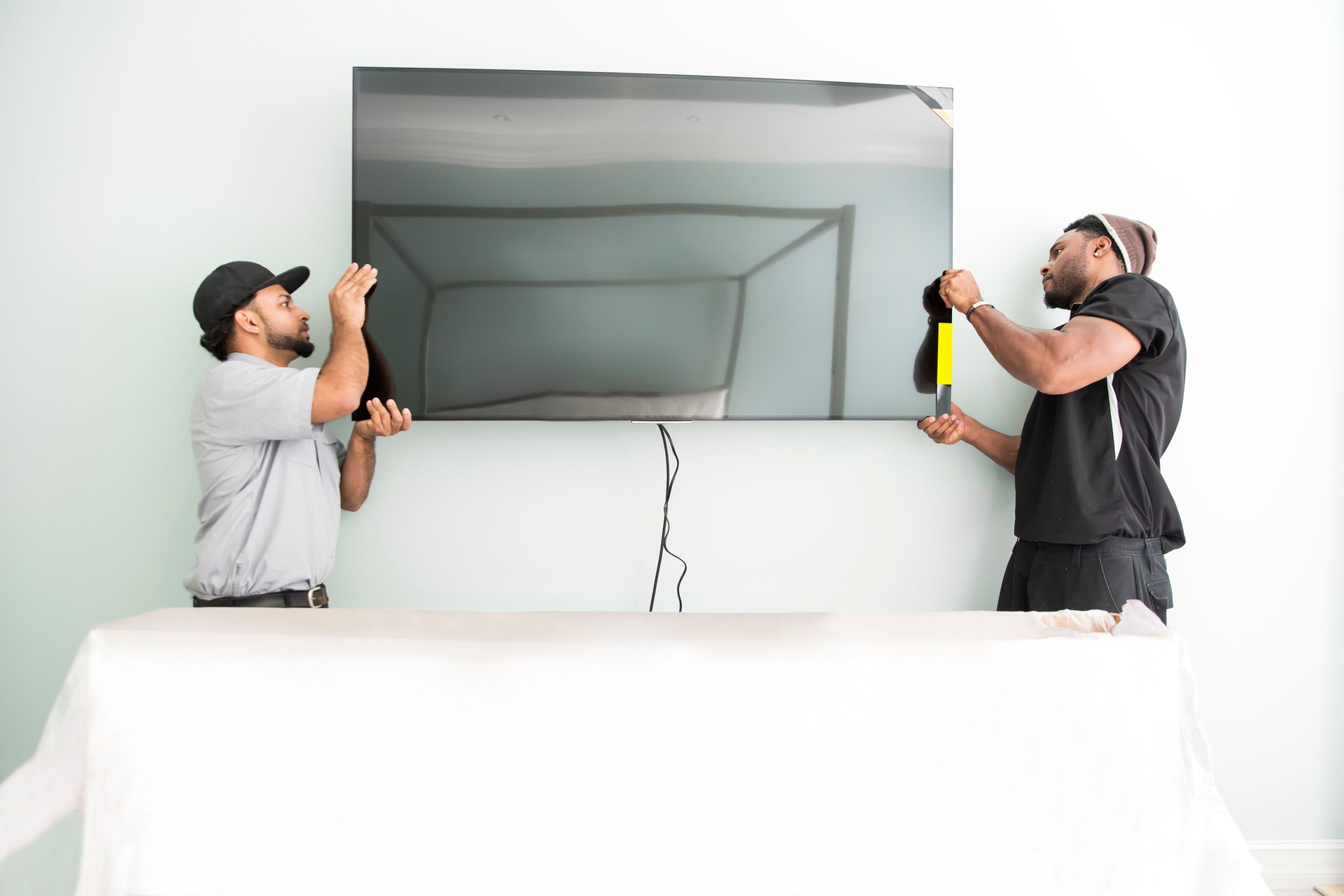 Series-Real televison installers hanging large flat screen TV on wall